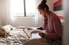 Sick woman on bed video chatting with doctor on laptop - iStock.jpg