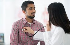 Doctor listening to a male patient's heartbeat with stethoscope
